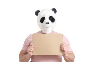 Man wearing a panda mask head holding white empty banner, isolated.
